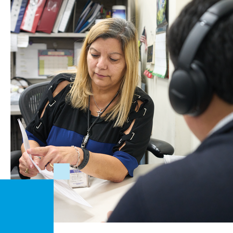 Year in Review Support Woman sitting at desk helping man with headphones