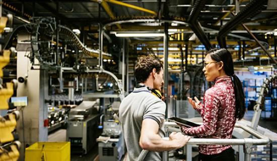 Image of two people in factory discussing work