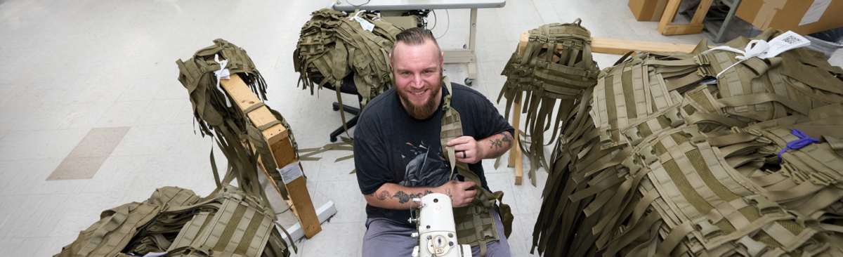 Year in Review Hero man sitting in chair sewing military gear