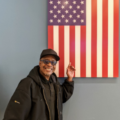 Bayaud Enterprises employee, Donald Dotson, stands besides an American flag.